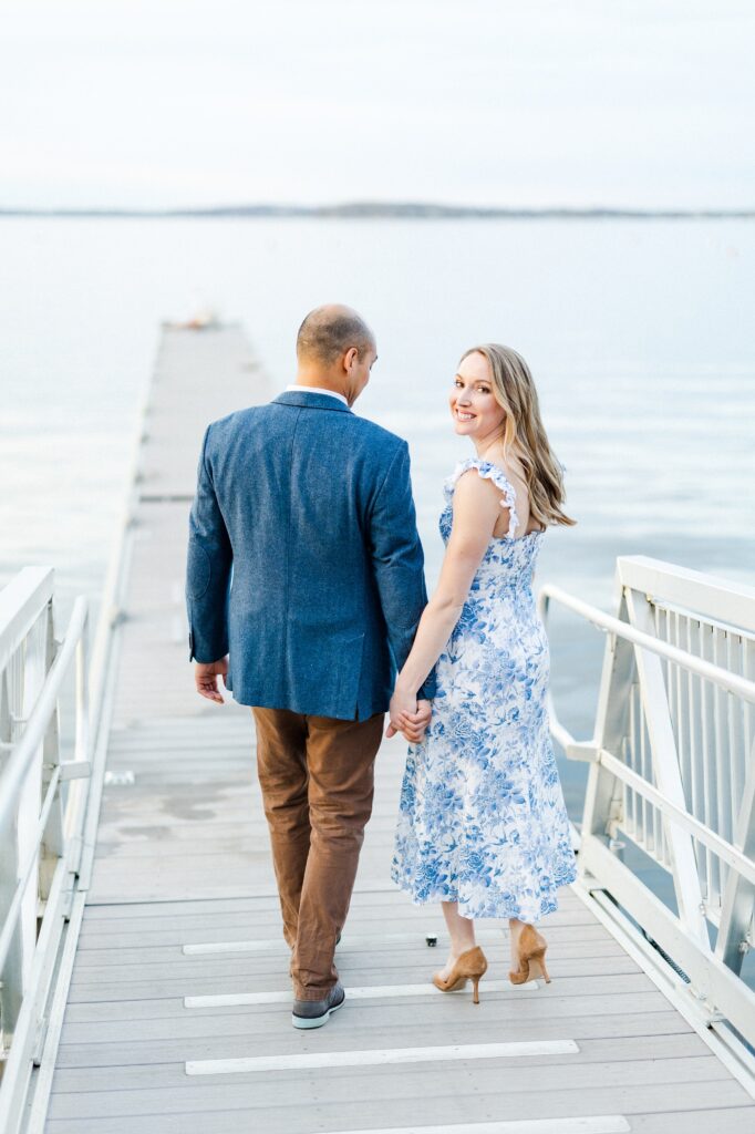 couple holding hands walking down a pier together in madison wisconsin