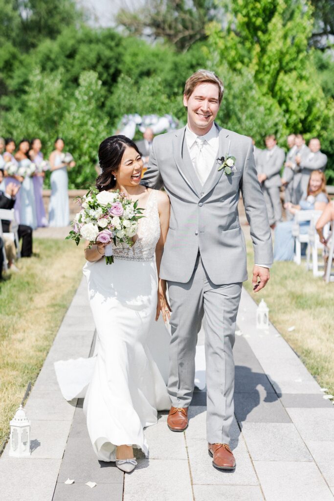 bride and groom smiling as they walk down the aisle after their ceremony at riverstone in fort atkinson
