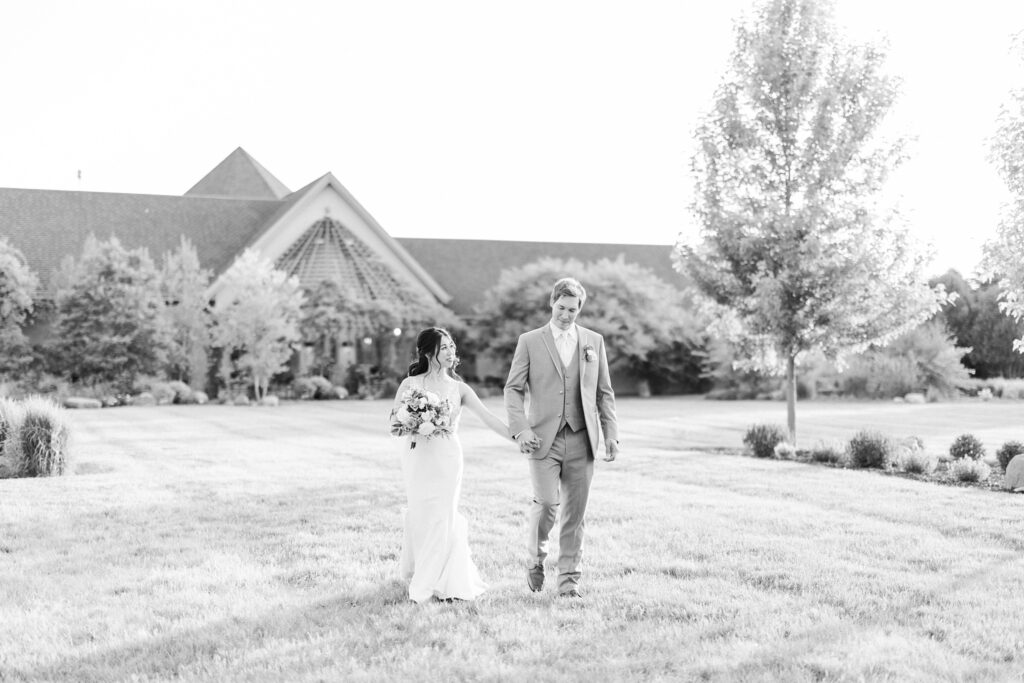 bride and groom walking across the lawn during their garden wedding