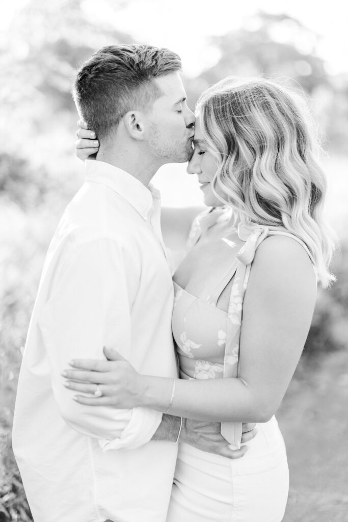 black and white image of a groom kissing his brides forehead