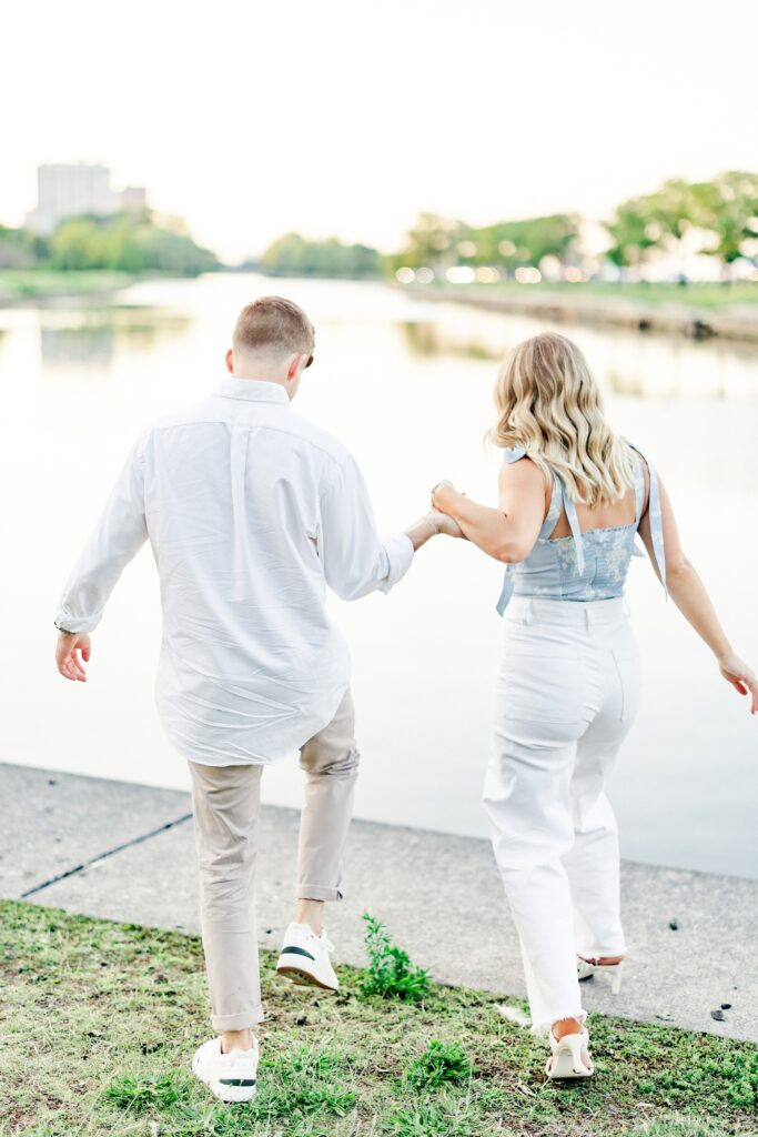 couple holding hands while walking towards the water