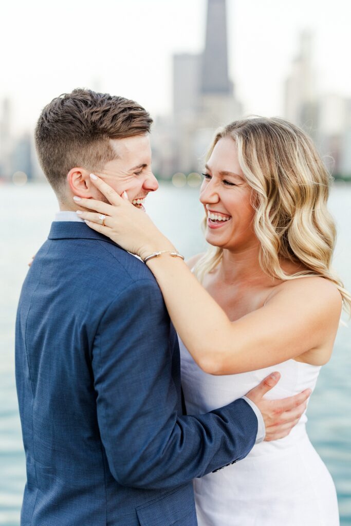 bride holding grooms face while they laugh