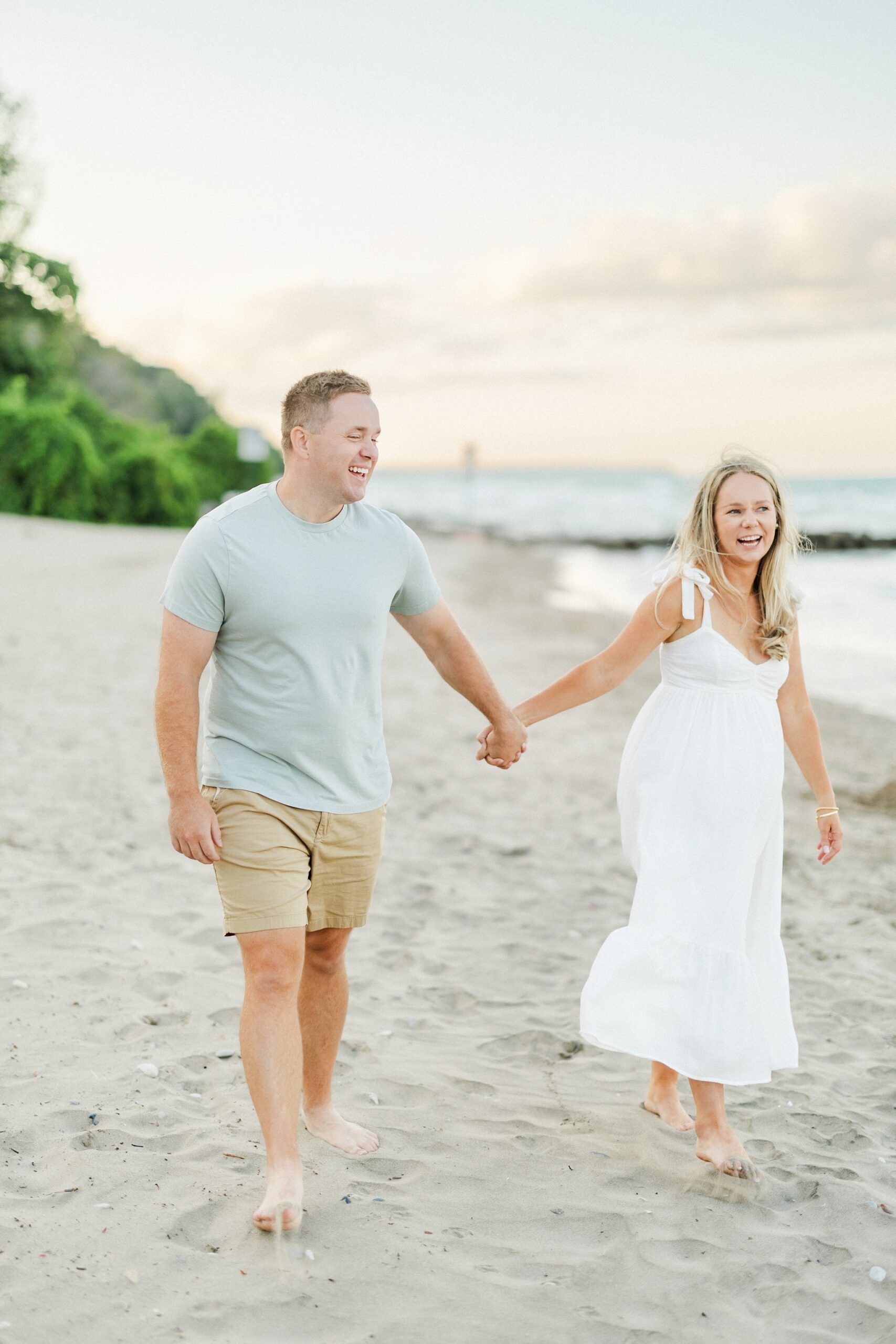 couple holding hands while laughing on the beach