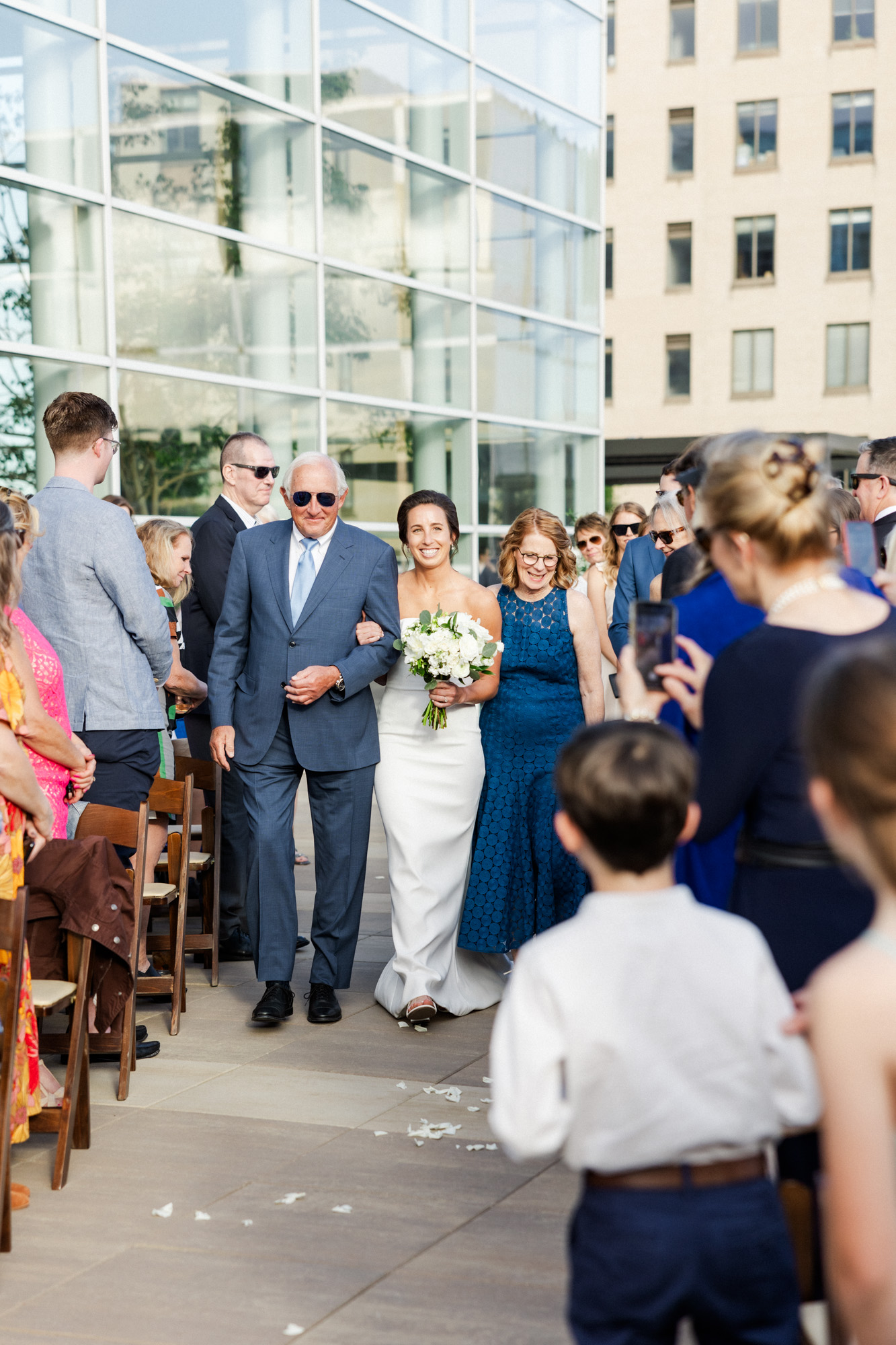 bride walking down the aisle with her parents during the rooftop ceremony